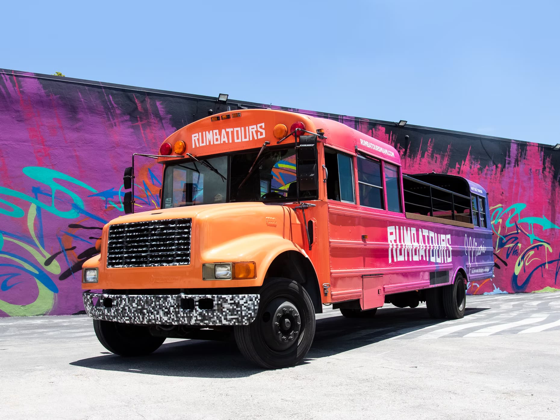 Open-air party bus driving through Miami with skyline in background